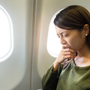 Woman experiencing anxiety during flight, sitting by airplane window seat